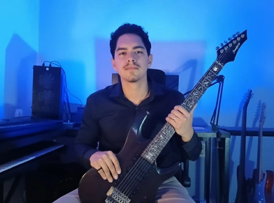 Alisson Vieira holding a guitar in his studio